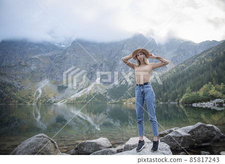 Young tourist woman in a hat with hands up on the top of the mountains 85817243