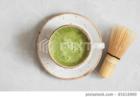 Matcha green tea. Homemade matcha latte and bamboo whisk on a gray concrete background closeup. Top view, flat lay. Matcha green tea. Homemade matcha latte and bamboo whisk on a gray concrete background closeup. Top view, flat lay. 85818900