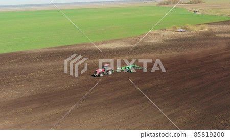 4K Aerial Elevated View.Tractor Plowing Field. Beginning Of Agricultural Spring Season. Cultivator Pulled By A Tractor In Countryside Rural Field Landscape 4K Aerial Elevated View.Tractor Plowing Field. Beginning Of Agricultural Spring Season. Cultivator Pulled By A Tractor In Countryside Rural Field Landscape 85819200