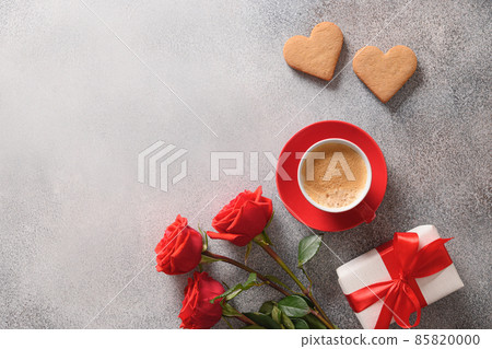 Coffee and two heart shaped cookies for Valentine's day. Bouquet of red roses and love gift. Coffee and two heart shaped cookies for Valentine's day. Bouquet of red roses and love gift. 85820000