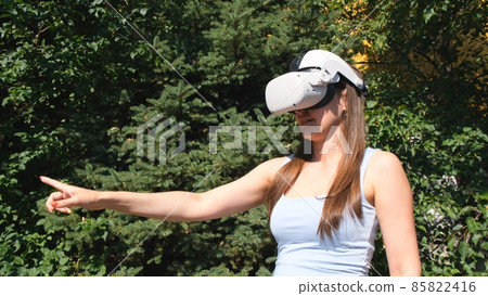 Female in virtual reality glasses controls the device with his hand against the background of green Female in virtual reality glasses controls the device with his hand against the background of green 85822416