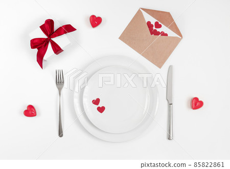Valentines day or romantic dinner background. Festive romantic table setting with candles and a gift on a white background. Valentine's card. Valentines day or romantic dinner background. Festive romantic table setting with candles and a gift on a white background. Valentine's card. 85822861
