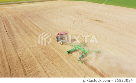 4K Aerial Elevated View.Tractor Plowing Field. Beginning Of Agricultural Spring Season. Cultivator Pulled By A Tractor In Countryside Rural Field Landscape. Cinematic Shot 85823054