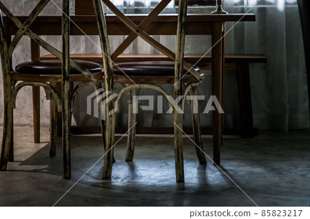 Two old wooden vintage chairs standing in an empty room near the window. 85823217