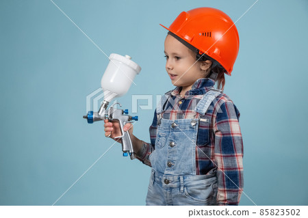 Cute little caucasian kid wearing hard hat with electric spray gun Cute little caucasian kid wearing hard hat with electric spray gun 85823502