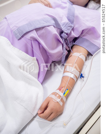 saline solution on hand of women patient in pink clothes lying on the hospital bed 85824517
