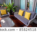 rattan outdoor furniture in a courtyard with garden beds and sandstone walls in the background 85824518
