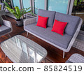 rattan outdoor furniture in a courtyard with garden beds and sandstone walls in the background 85824519