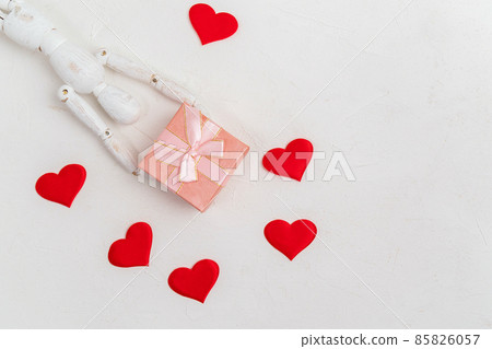 Valentines Day background. A gift box with a wooden mannequin on a white background. Flat lay. Copy space 85826057