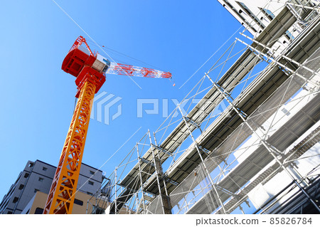 Clear blue sky and colorful construction cranes at a building construction site 85826784