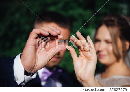 newlyweds look at wedding rings at a shallow depth of field 85827379