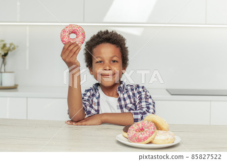 Cute little child and colorful donuts in his hand indoor on white 85827522