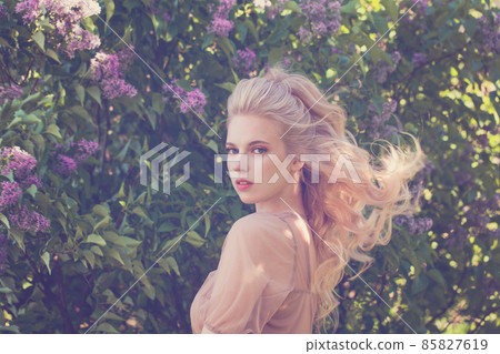 Pretty young woman in spring flowers garden Pretty young woman in spring flowers garden 85827619