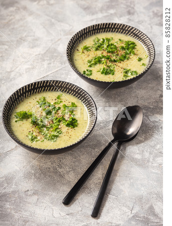 Homemade broccoli cream soup on light background. Homemade broccoli cream soup on light background. 85828212