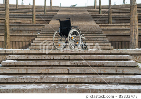 Wheelchair by the stairs without people outdoors.  85832475