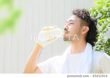 A man who works outside to rehydrate in the hot weather. 85832914