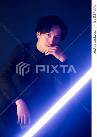 A man illuminated by blue light in the dark 85834370