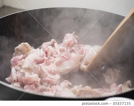 Fry the pork in an iron wok 85837135