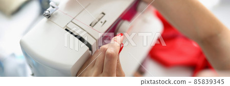 Female hands insert thread into sewing machine Female hands insert thread into sewing machine 85839345