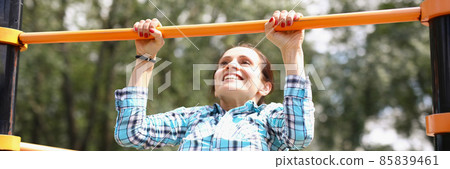 Woman hanging on horizontal bar and smiling 85839461