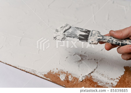 A spatula, the process of applying a layer of putty on a sheet of fiberboard. production of a textural background for subject shooting. A spatula, the process of applying a layer of putty on a sheet of fiberboard. production of a textural background for subject shooting. 85839885
