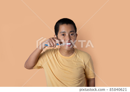 Young man brushing teeth, cleaning teeth isolated on orange studio background. health care dental concept. 85840621