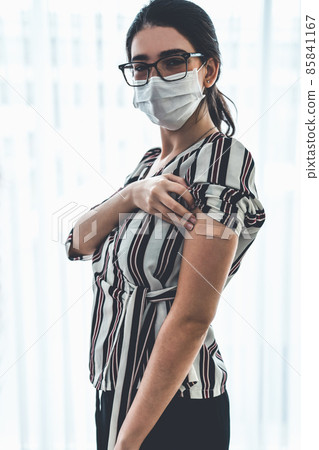 Young woman showing COVID-19 vaccine bandage merrily 85841167