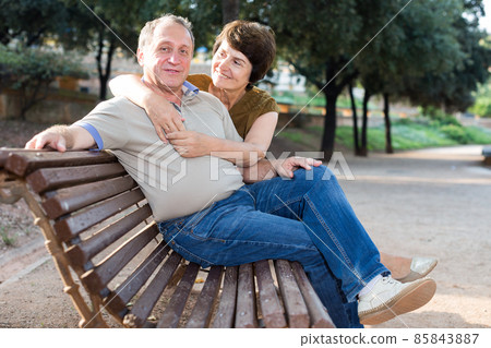 middleaged male and female posing on bench middleaged male and female posing on bench 85843887