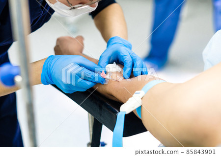 The doctor inserts a dropper needle into the patient's arm.  85843901