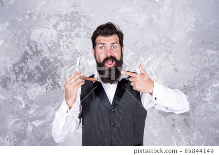 handsome brutal man barber with beard pointing finger on barbershop retro razor, hair salon. handsome brutal man barber with beard pointing finger on barbershop retro razor, hair salon. 85844149
