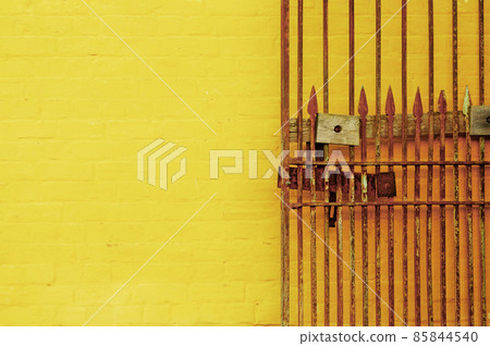 Rusty antique lock gate and bright yellow wall Rusty antique lock gate and bright yellow wall 85844540