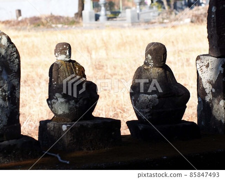 Close-up of a stone Buddha bathed in sunlight through the trees (a shrine in a rice field) Close-up of a stone Buddha bathed in sunlight through the trees (a shrine in a rice field) 85847493