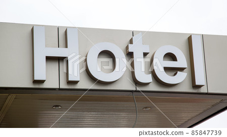 The inscription Hotel above the entrance to the building against the background of gray rainy sky The inscription Hotel above the entrance to the building against the background of gray rainy sky 85847739