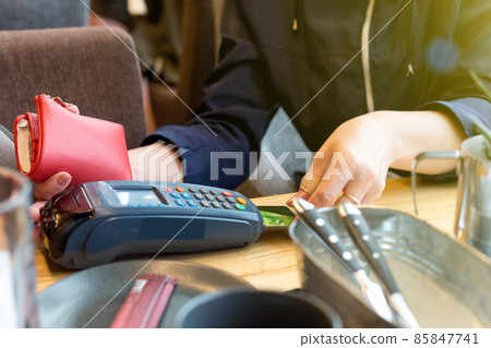 A woman pays with a bank credit card for lunch in a restaurant via a wireless terminal. The concept of acquiring services and Internet transfers A woman pays with a bank credit card for lunch in a restaurant via a wireless terminal. The concept of acquiring services and Internet transfers 85847741