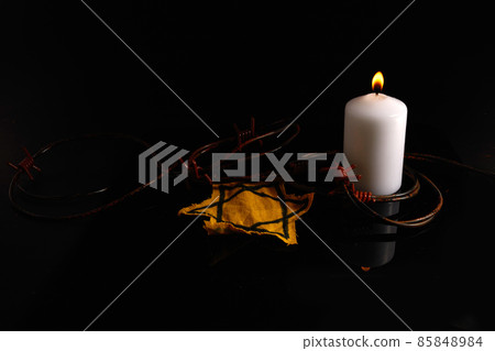 Holocaust memory day. Arbed wire and burning candle on black background Holocaust memory day. Arbed wire and burning candle on black background 85848984