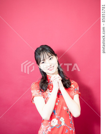 慶祝中國傳統旗幟女旗袍在紅色背景上展示一隻手。 慶祝中國傳統旗幟女旗袍在紅色背景上展示一隻手。 85851781