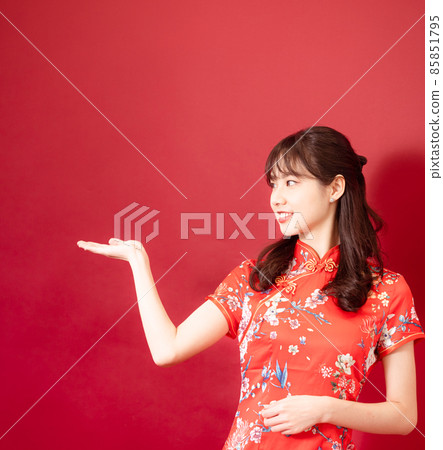 一位身著旗袍的美麗女子，紅色的背景，臉上帶著微笑。 85851795