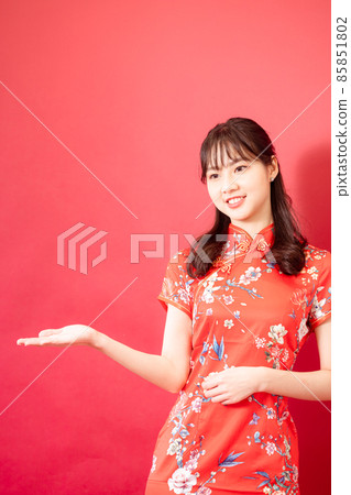 一位身著旗袍的美麗女子，紅色的背景，臉上帶著微笑。 85851802