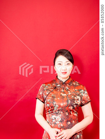 Beautiful mature woman by Cheongsam Red Flag or dress, smiling on a red background. 85852000