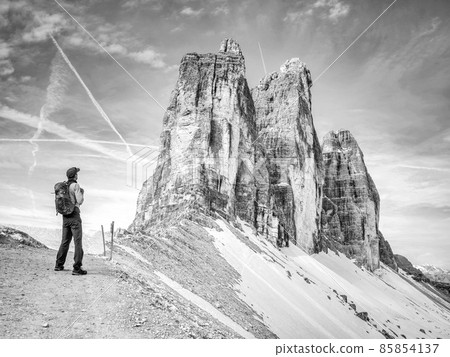 Backpacker on trip aound Tre Cime di Lavaredo in sunny April morning. Backpacker on trip aound Tre Cime di Lavaredo in sunny April morning. 85854137