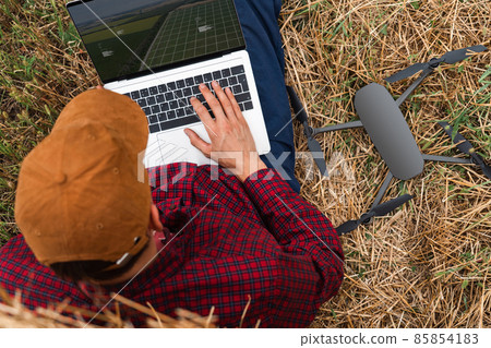 Farmer with laptop and drone on the field 85854183