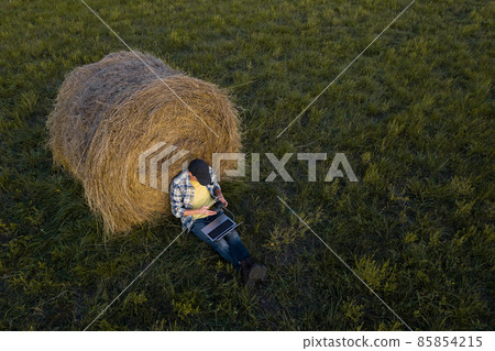 Farmer with laptop on the field. Drone point of view. Farmer with laptop on the field. Drone point of view. 85854215