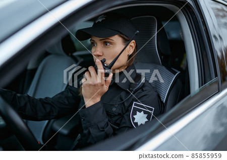 Policewoman using radio patrolling street in car 85855959