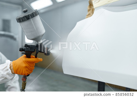 Technician in safety clothing spraying car paint 85856032