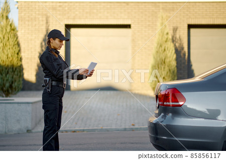 Woman police officer check stopped car number Woman police officer check stopped car number 85856117