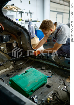 Workman fixing bolt during car body repair Workman fixing bolt during car body repair 85856126