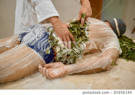 Man getting massage with broom in bath 85856149