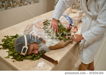Man getting massage with broom in bath 85856160