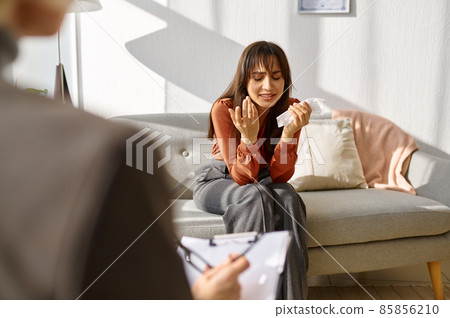 Woman crying crumpling napkins talking to psychologist 85856210
