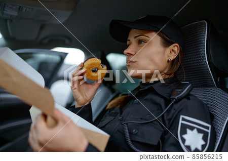 Woman police officer eating donut in car 85856215